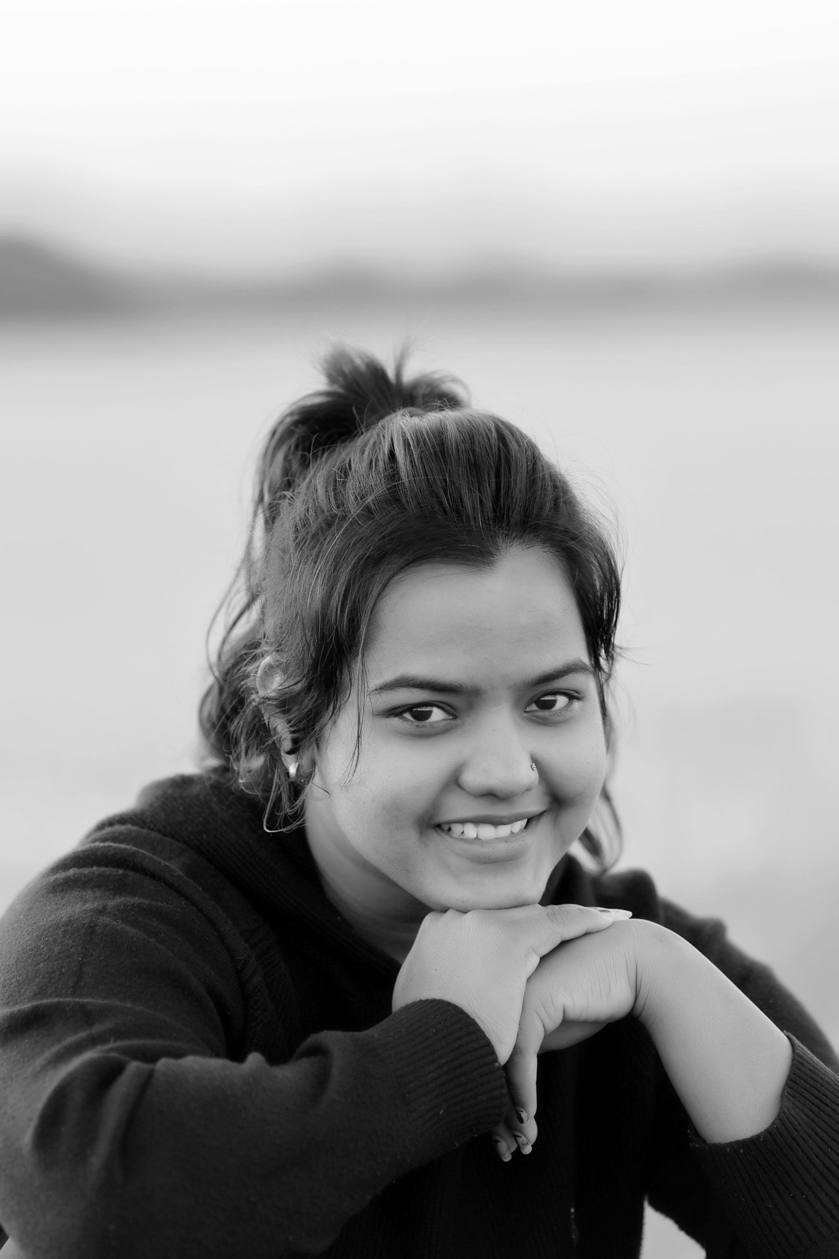 A candid black and white portrait of an adult woman smiling outdoors.